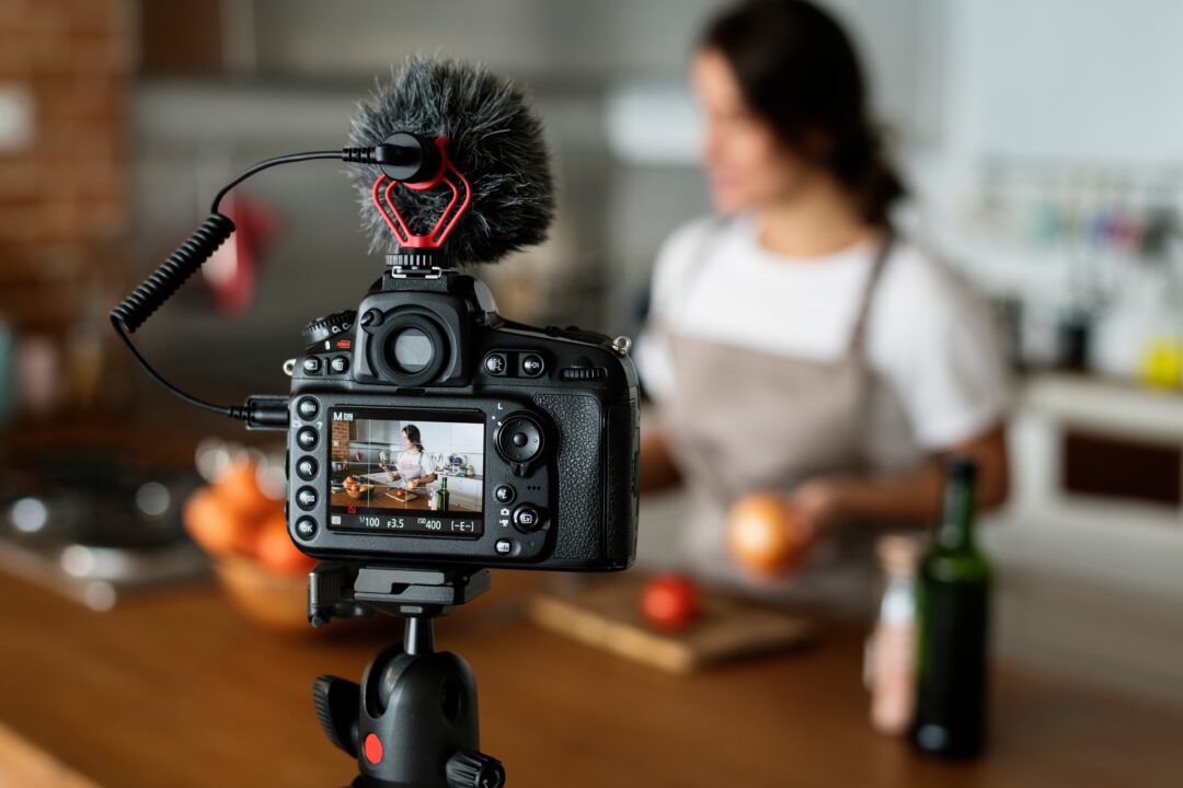 Eine Frau macht ein Kochlivestream und wird von einer Kamera gefilmt